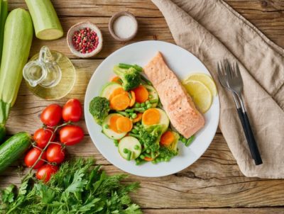 une assiette de saumon, brocoli, tomates, concombres et.