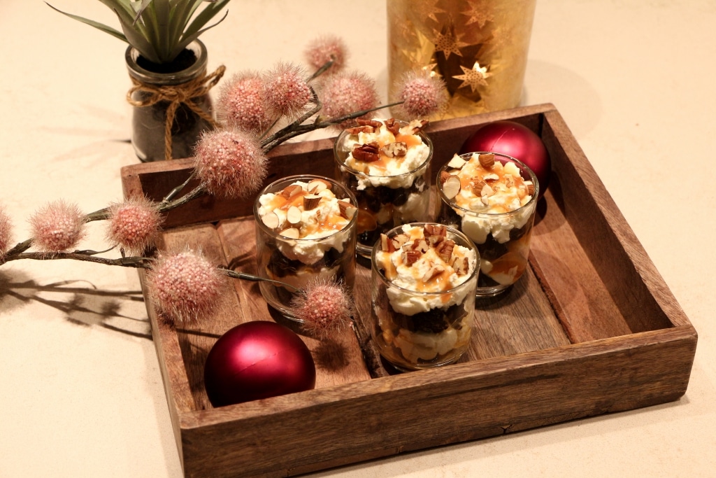 un plateau en bois garni de desserts à côté d'un vase de fleurs.