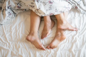 deux personnes allongées dans un lit sous une couverture.