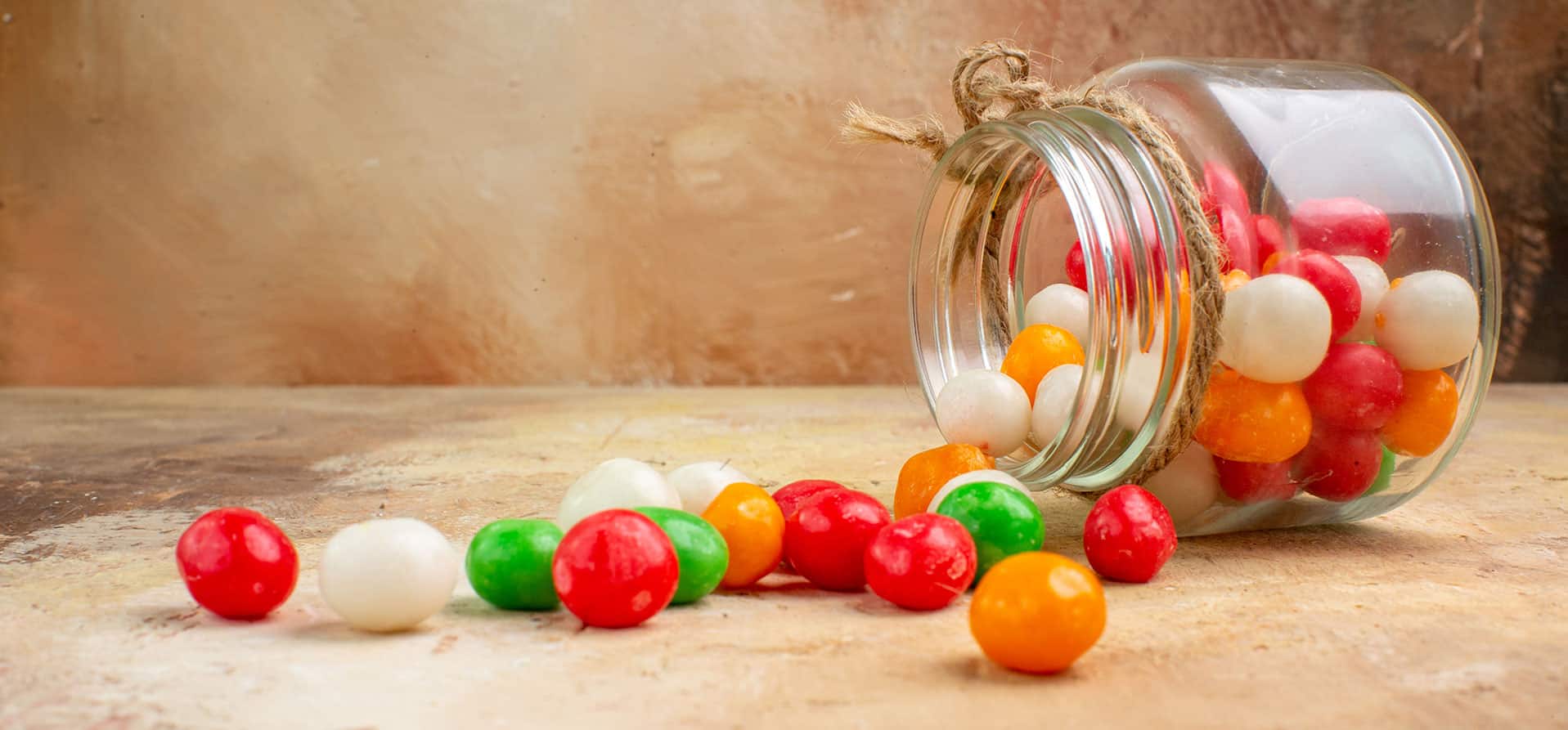 Bonbons colorés dans un bocal en verre sur une table en bois.