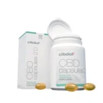 Un récipient ouvert de capsules molles Cibdol 5% CBD 2.0 révèle des capsules dorées, positionnées à côté de sa boîte d'emballage.