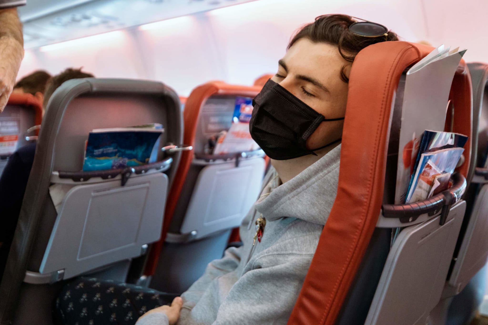 un homme portant un masque facial assis dans un avion.