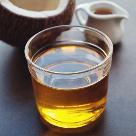 un verre d'huile à côté d'une noix de coco sur une table.